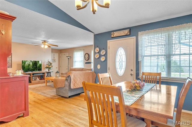 dining room featuring ceiling fan, light wood-style flooring, and vaulted ceiling
