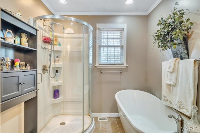 bathroom featuring a stall shower, a freestanding bath, tile patterned flooring, ornamental molding, and baseboards