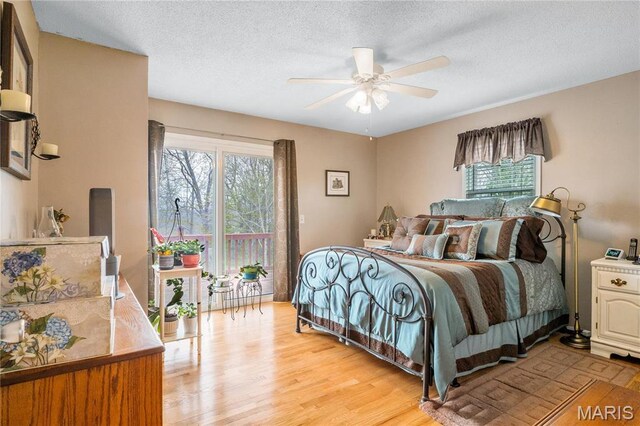 bedroom with multiple windows, light wood-type flooring, a textured ceiling, access to outside, and ceiling fan