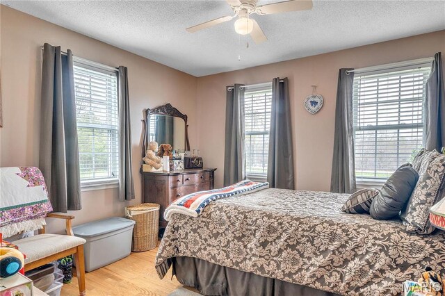 bedroom with light wood finished floors, a textured ceiling, and ceiling fan