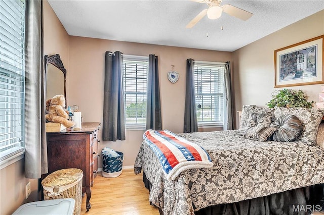 bedroom with wood finished floors, a ceiling fan, a textured ceiling, and baseboards