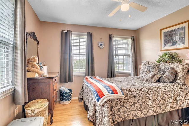 bedroom featuring wood finished floors, a textured ceiling, a ceiling fan, and baseboards
