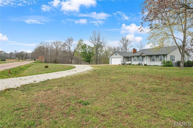 view of grassy yard with a garage and driveway