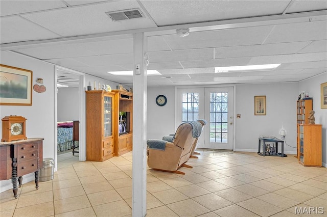 living room with a paneled ceiling, light tile patterned flooring, and baseboards