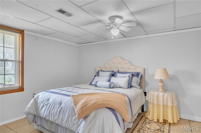 bedroom featuring tile patterned flooring, baseboards, a drop ceiling, and a ceiling fan