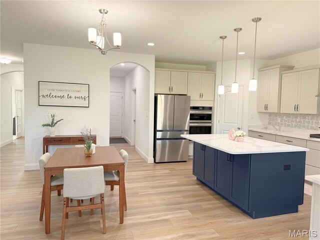 536 Edison Way, Wentzville, MO 63385 - kitchen with appliances with stainless steel finishes, arched walkways, a center island, light countertops, and backsplash