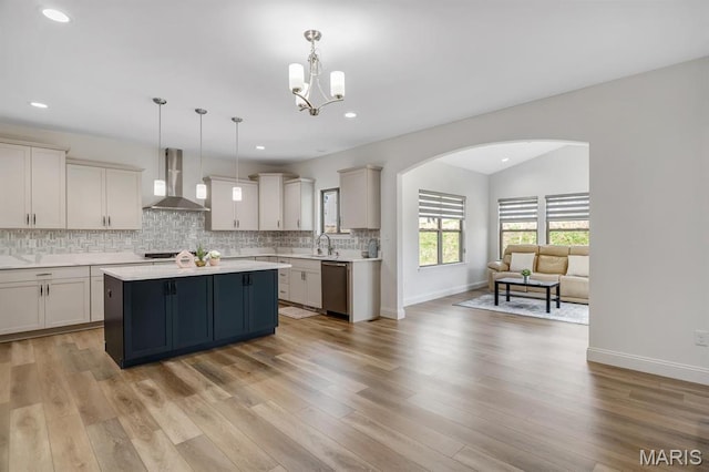 536 Edison Way, Wentzville, MO 63385 - kitchen featuring wall chimney exhaust hood, arched walkways, light countertops, tasteful backsplash, and a sink