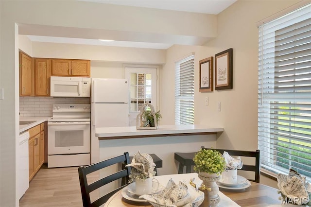 1707 Mayenne Ct Unit B, Saint Louis, MO 63125 - kitchen with white appliances, light countertops, decorative backsplash, light wood-style floors, and brown cabinetry