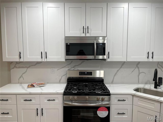 5811 Dewey Ave, Saint Louis, MO 63116 - kitchen featuring stainless steel appliances, a sink, white cabinets, and decorative backsplash