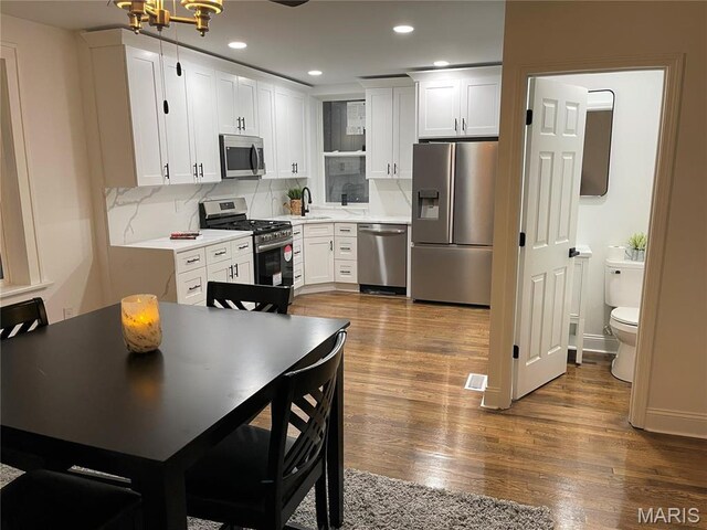 5811 Dewey Ave, Saint Louis, MO 63116 - kitchen with appliances with stainless steel finishes, a sink, white cabinetry, wood finished floors, and tasteful backsplash