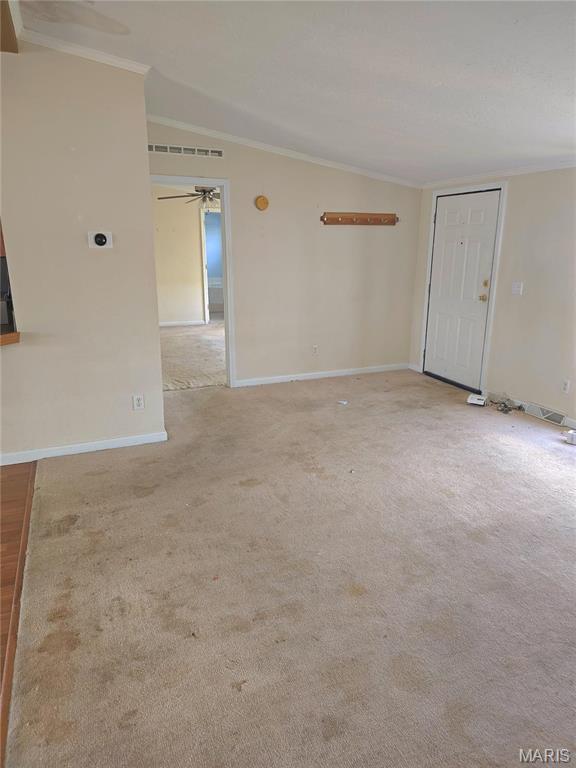 empty room with crown molding, ceiling fan, baseboards, and light carpet