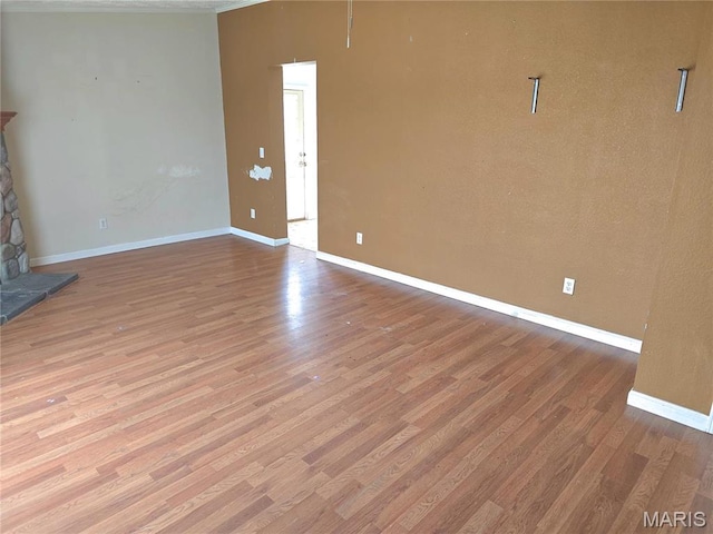 unfurnished living room with wood finished floors, baseboards, and ornamental molding