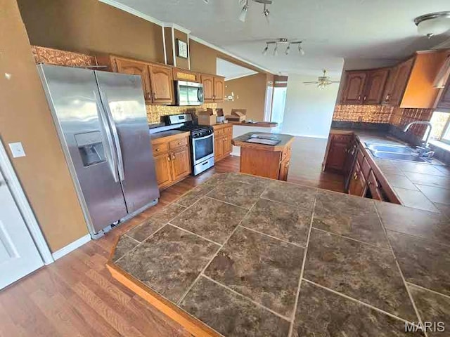 kitchen featuring stainless steel appliances, tasteful backsplash, a center island, a peninsula, and ceiling fan