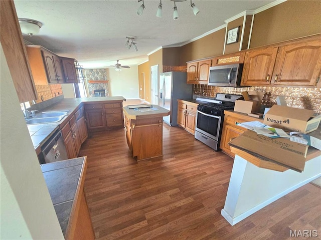 kitchen featuring appliances with stainless steel finishes, a peninsula, ornamental molding, a sink, and decorative backsplash