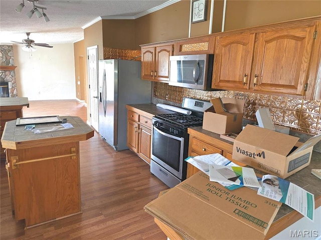 kitchen featuring stainless steel appliances, crown molding, wood finished floors, ceiling fan, and tile countertops