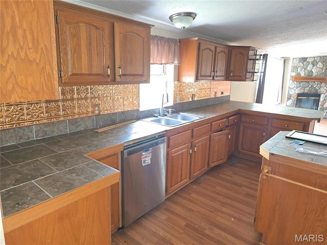 kitchen featuring stainless steel dishwasher, a sink, tile counters, tasteful backsplash, and a textured ceiling