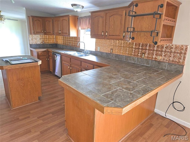 kitchen with a sink, dishwasher, wood finished floors, and brown cabinetry