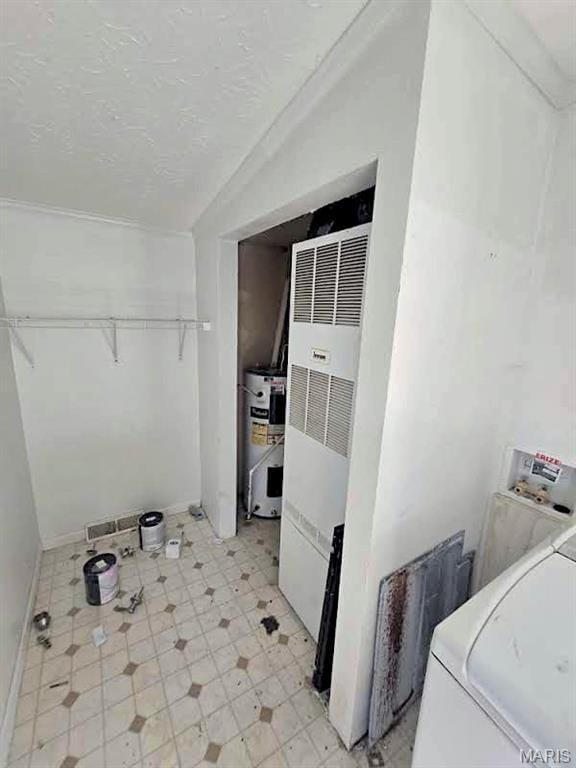 clothes washing area with water heater, a heating unit, washer / clothes dryer, baseboards, and a textured ceiling