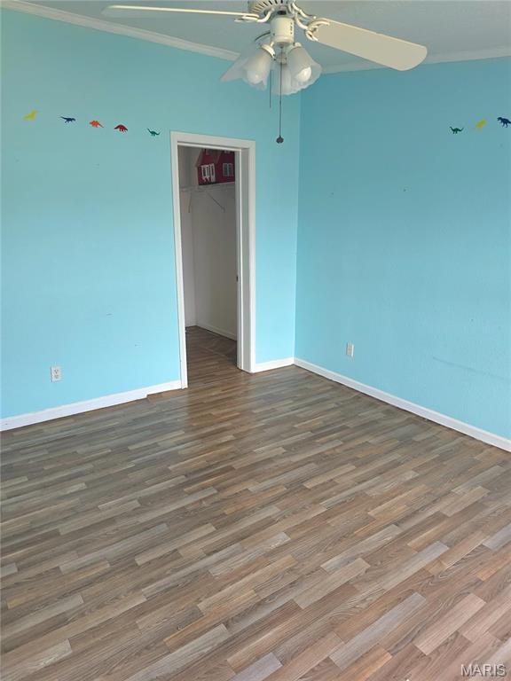 unfurnished room with a ceiling fan, crown molding, baseboards, and wood finished floors