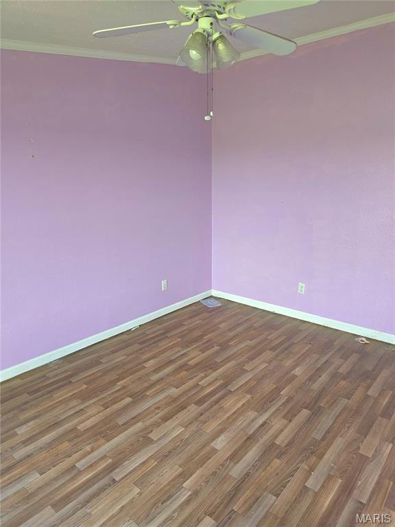 spare room featuring ceiling fan, crown molding, baseboards, and wood finished floors