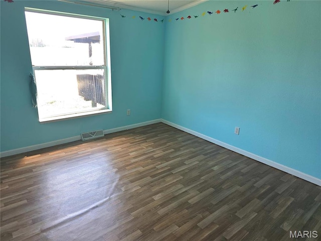 unfurnished room featuring dark wood-style flooring, baseboards, and crown molding