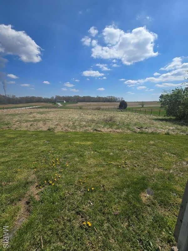view of grassy yard with a rural view