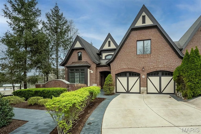 tudor house with brick siding, a garage, and driveway