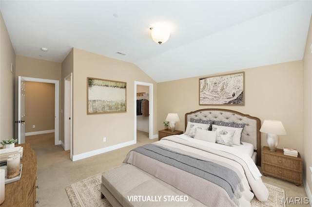bedroom with light colored carpet, baseboards, a walk in closet, and vaulted ceiling