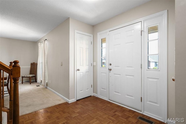 entrance foyer featuring baseboards, a textured ceiling, and stairway
