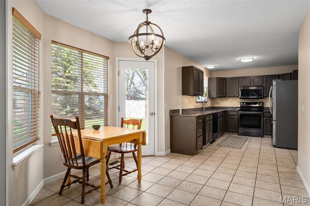 kitchen with stainless steel appliances, a sink, a chandelier, backsplash, and light tile patterned floors