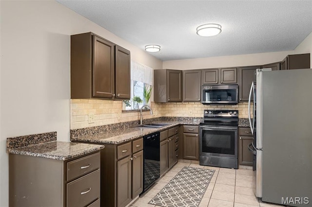 kitchen with stainless steel appliances, a sink, tasteful backsplash, light tile patterned flooring, and dark brown cabinetry