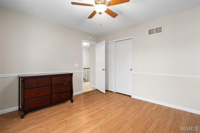 unfurnished bedroom with light wood-style flooring, baseboards, a closet, and a ceiling fan