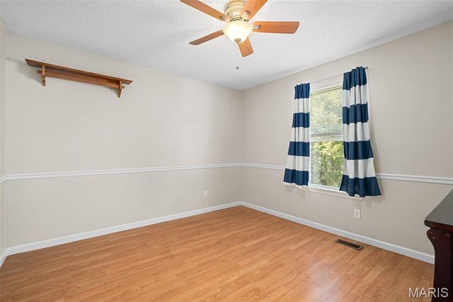unfurnished room featuring wood finished floors, baseboards, a textured ceiling, and a ceiling fan