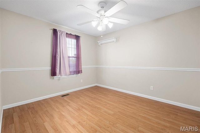 empty room with light wood-style floors, a ceiling fan, and baseboards