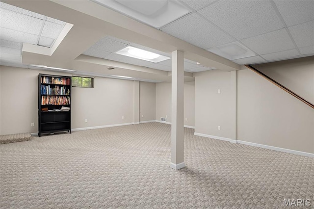 basement featuring carpet, a drop ceiling, and baseboards