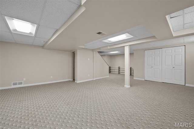 finished below grade area with carpet floors, a paneled ceiling, and baseboards