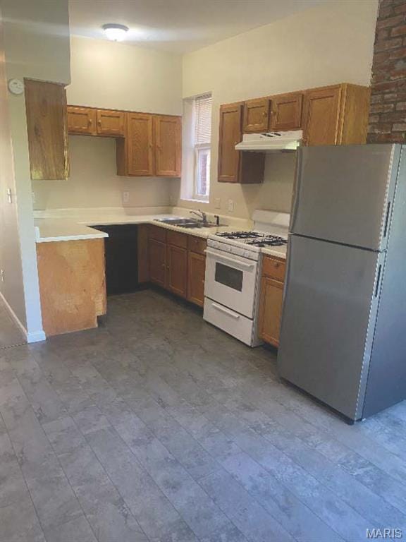 1208 N Euclid Ave, Saint Louis, MO 63113 - kitchen with freestanding refrigerator, white gas range oven, under cabinet range hood, a sink, and brown cabinetry