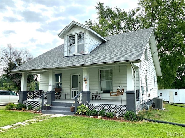 111 SE St, Wellsville, MO 63384 - bungalow-style house featuring covered porch, central AC unit, a shingled roof, and a front lawn