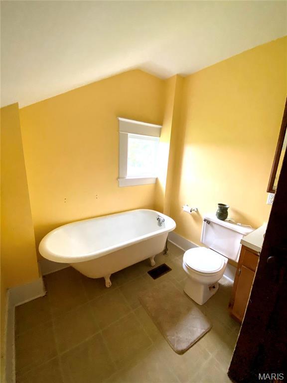 111 SE St, Wellsville, MO 63384 - bathroom with toilet, a soaking tub, vanity, lofted ceiling, and tile patterned floors