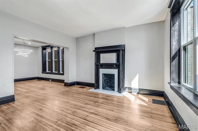 4021 Winnebago St, Saint Louis, MO 63116 - unfurnished living room featuring wood finished floors, a fireplace with flush hearth, baseboards, and a chandelier