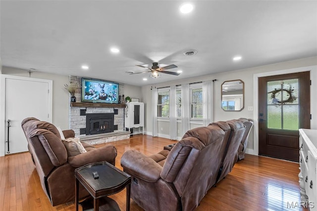 living room with wood finished floors, ceiling fan, recessed lighting, a stone fireplace, and baseboards