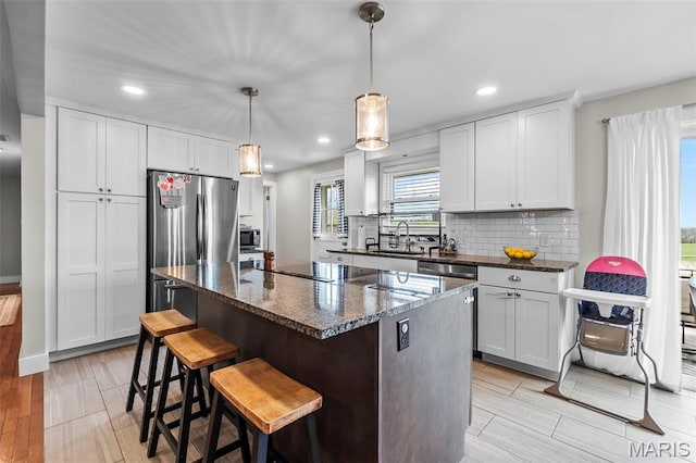 kitchen featuring a sink, a center island, recessed lighting, dark stone counters, and decorative backsplash