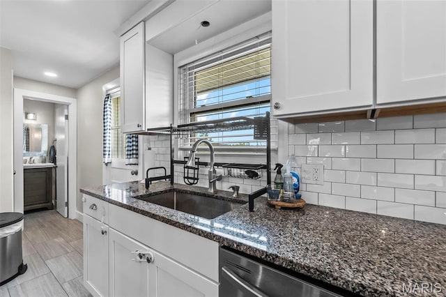 kitchen with a sink, white cabinets, dark stone countertops, tasteful backsplash, and recessed lighting