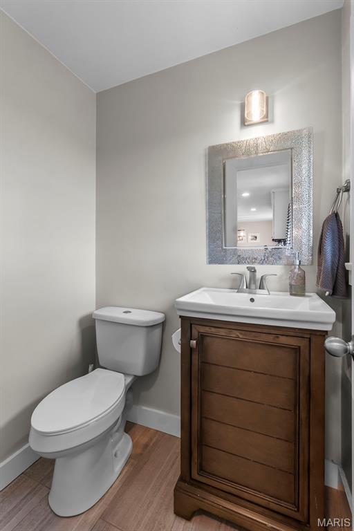 bathroom featuring wood finished floors, toilet, baseboards, and vanity