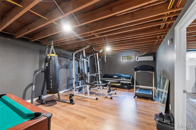 exercise area with wood finished floors and a wall mounted air conditioner