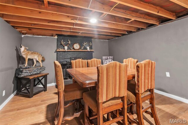 dining space with wood finished floors, baseboards, and a brick fireplace