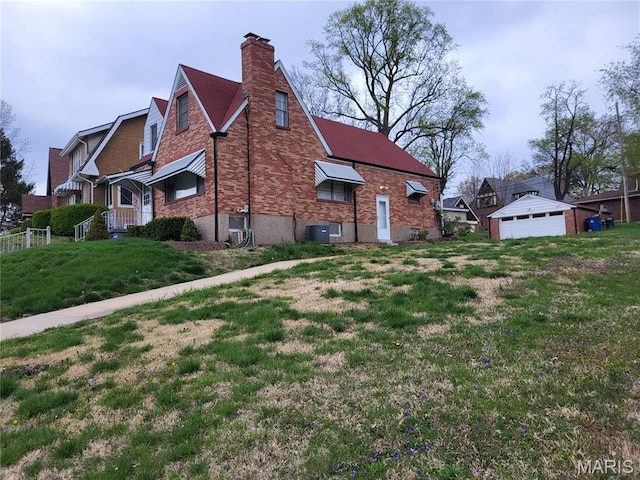 8303 Knollwood Dr, Saint Louis, MO 63121 - view of property exterior with a chimney, a detached garage, brick siding, a yard, and central AC unit