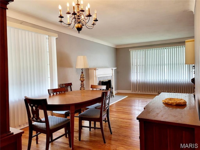8303 Knollwood Dr, Saint Louis, MO 63121 - dining room featuring light wood-style floors, a fireplace, a chandelier, and baseboards