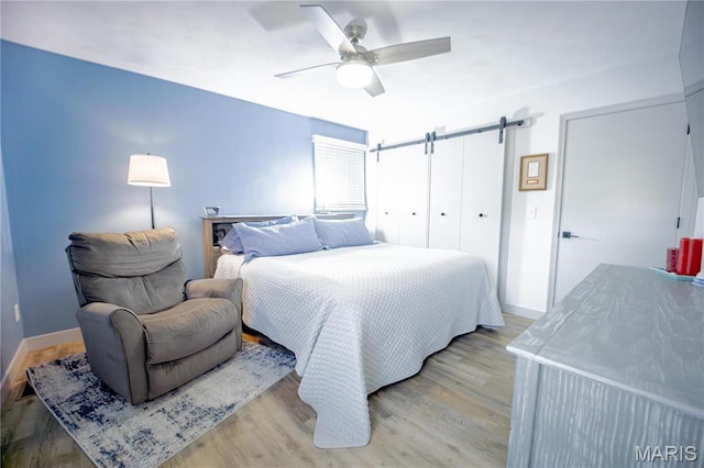 5826 Grandview Ter, Waterloo, IL 62298 - bedroom featuring light wood-style floors, a barn door, baseboards, and ceiling fan