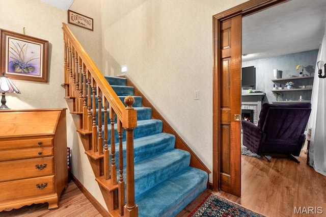 411 S High St, Belleville, IL 62220 - stairway with wood finished floors, a stone fireplace, and baseboards